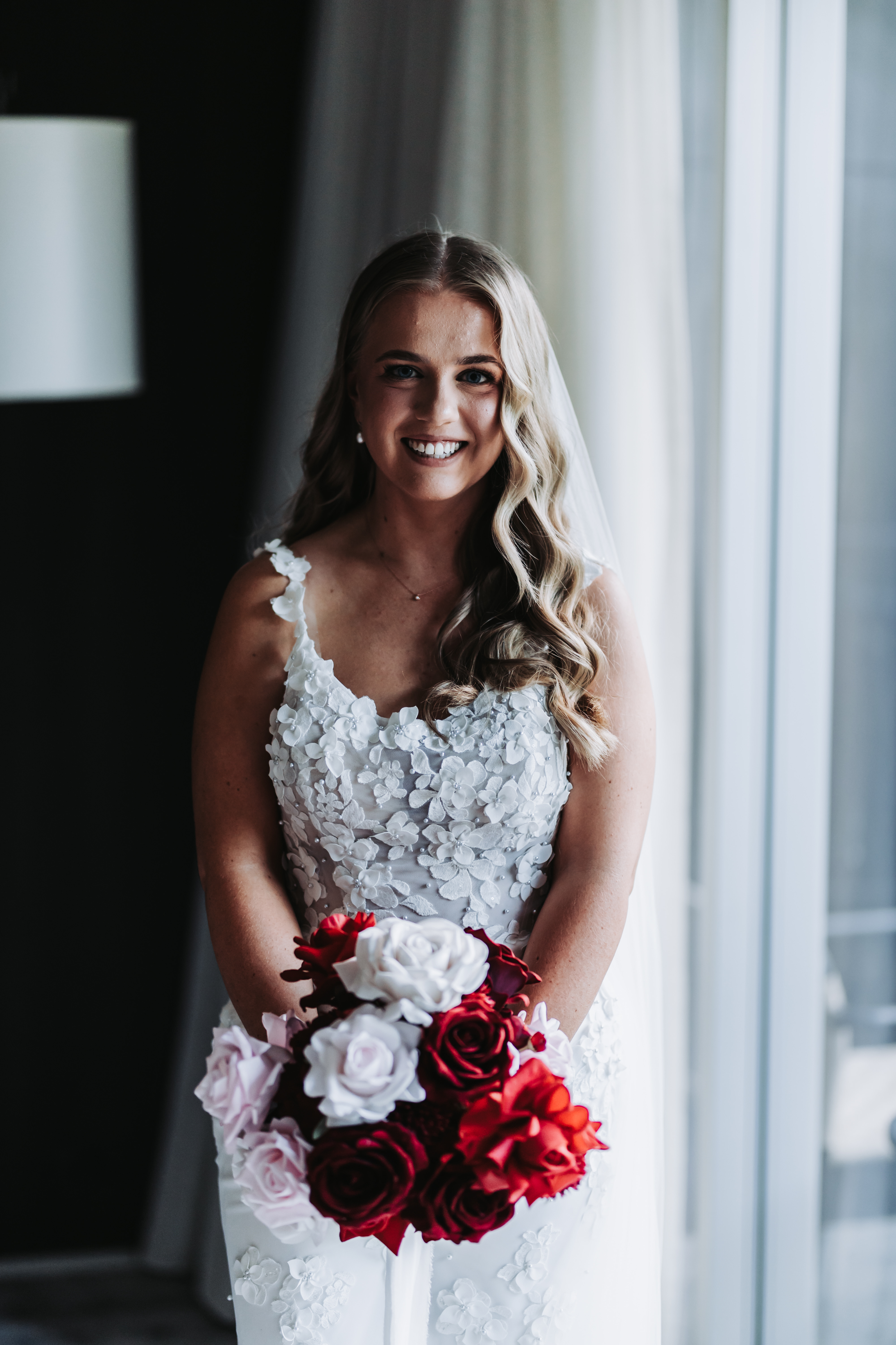 Bride in white beaded gown holding red, pink and white bridal bouquet, Mayflower Designs Canberra wedding flowers and styling.