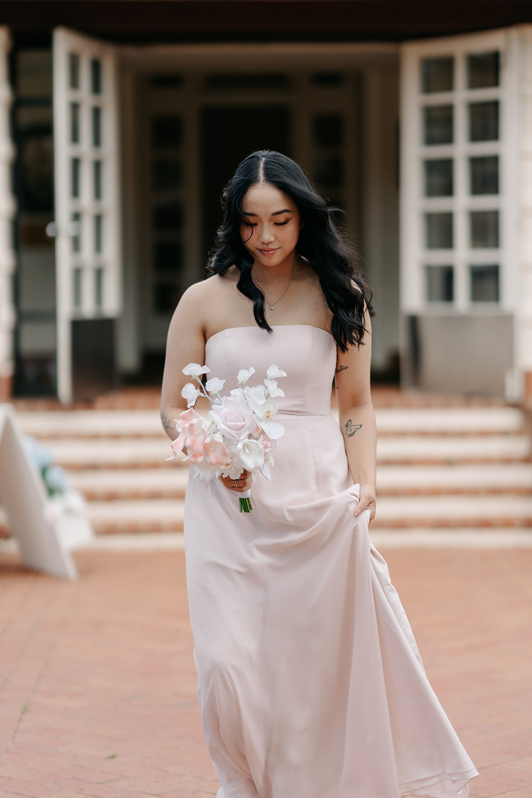 Bride holding pale pink and white orchid bouquet at Canberra wedding venue with modern architecture backdrop